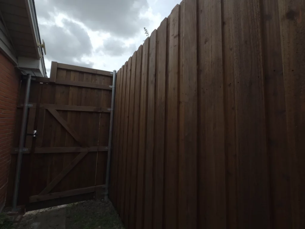 6 ft stained cedar privacy fence running along a side yard and meeting the existing gate in Grand Prairie, TX
