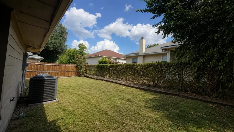 Old chain link fence and thin hedge in an Irving, TX backyard before cedar fence installation