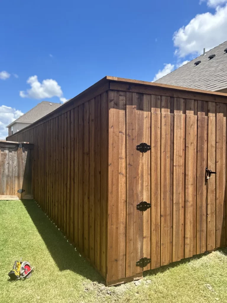 Board-on-board cedar fence in Grand Prairie, TX with a stained gate on black strap hinges