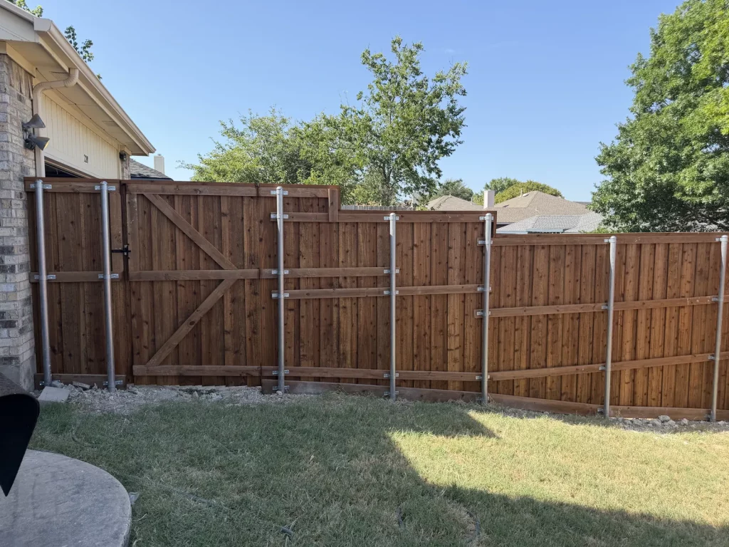 Rail side of a cedar fence in Cedar Hill, TX showing the new metal posts and braced gate frame