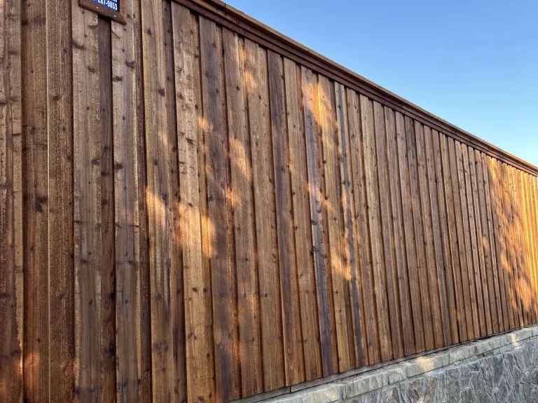 Finished 8 ft cedar fence in Plano, TX with board-on-board pickets and a capped top line above a stone base