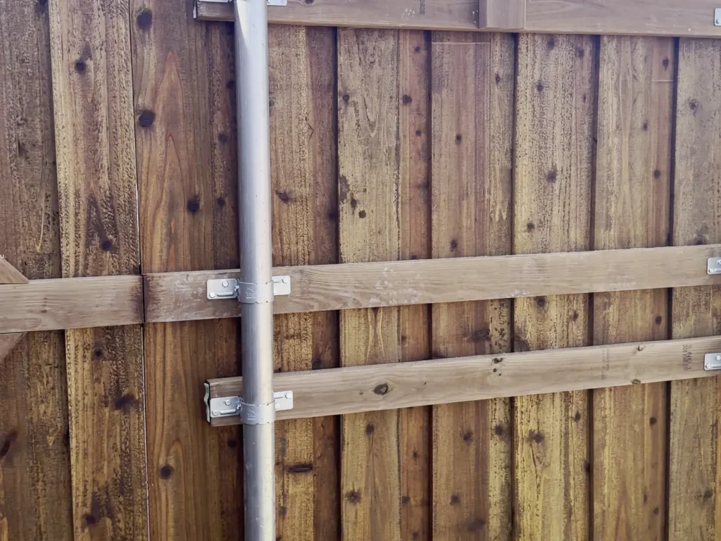 Close view of cedar rails, metal post brackets and the treated baseboard on a fence in Cedar Hill, TX