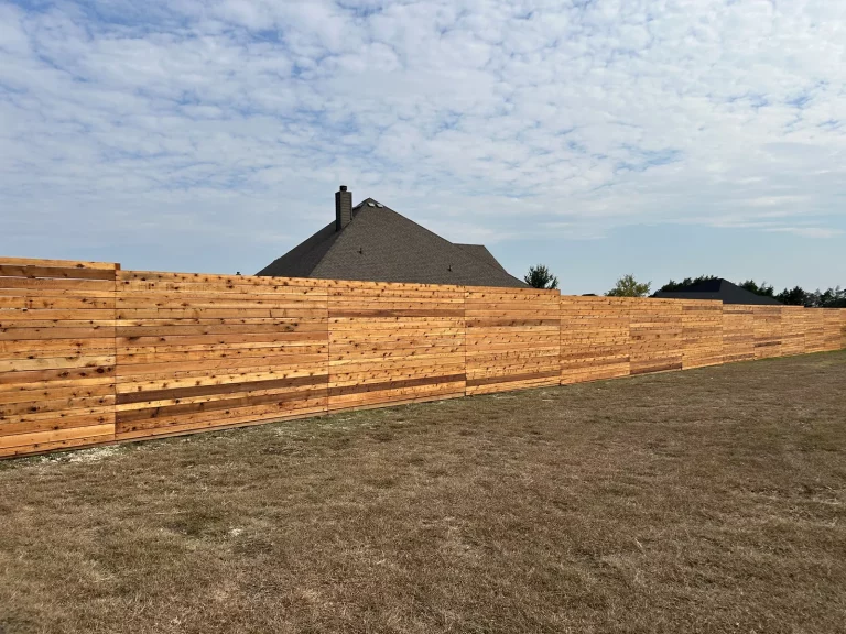 Long run of horizontal cedar fence stretching across an open property in [City], TX