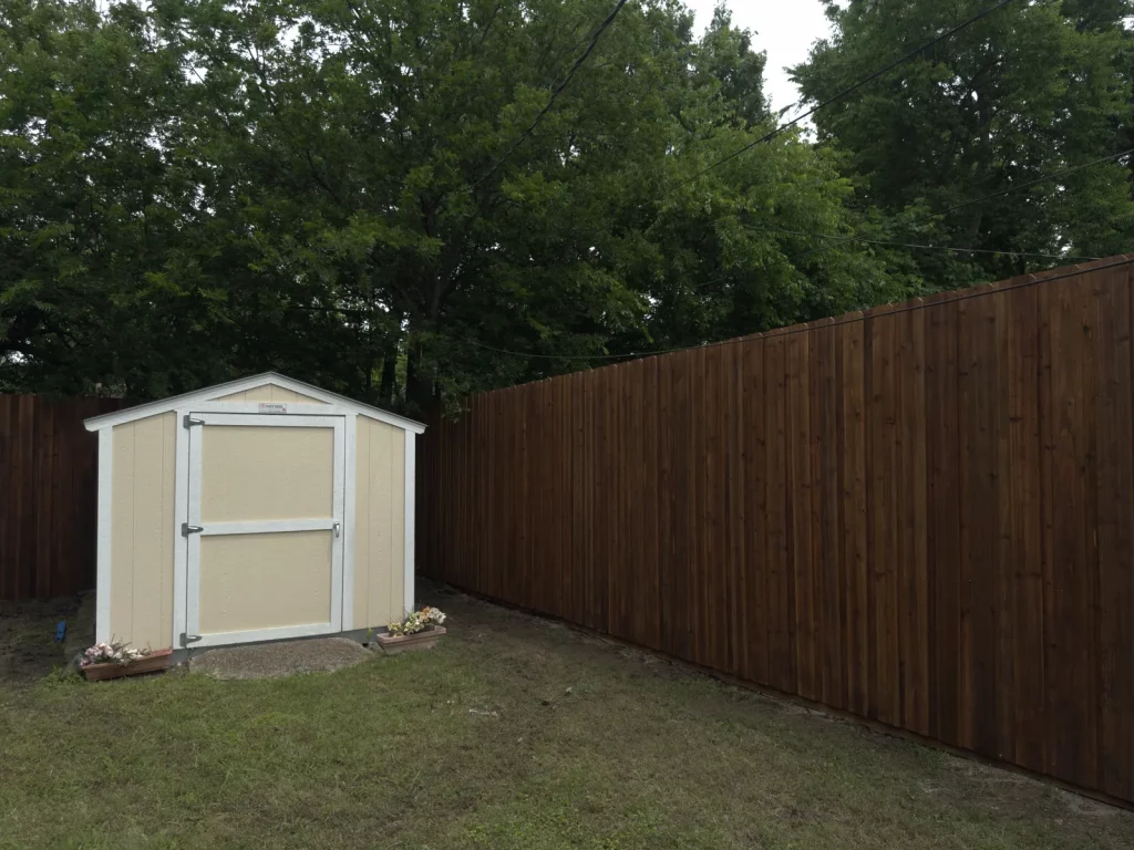 Finished side by side cedar fence in Grand Prairie, TX running along a backyard property line beside a storage shed