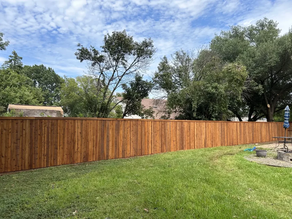 Stained cedar fence running the length of a backyard boundary in Arlington, TX