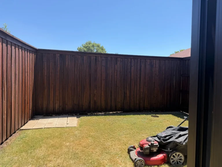 Freshly restained dark cedar fence corner in a backyard in Desoto, TX