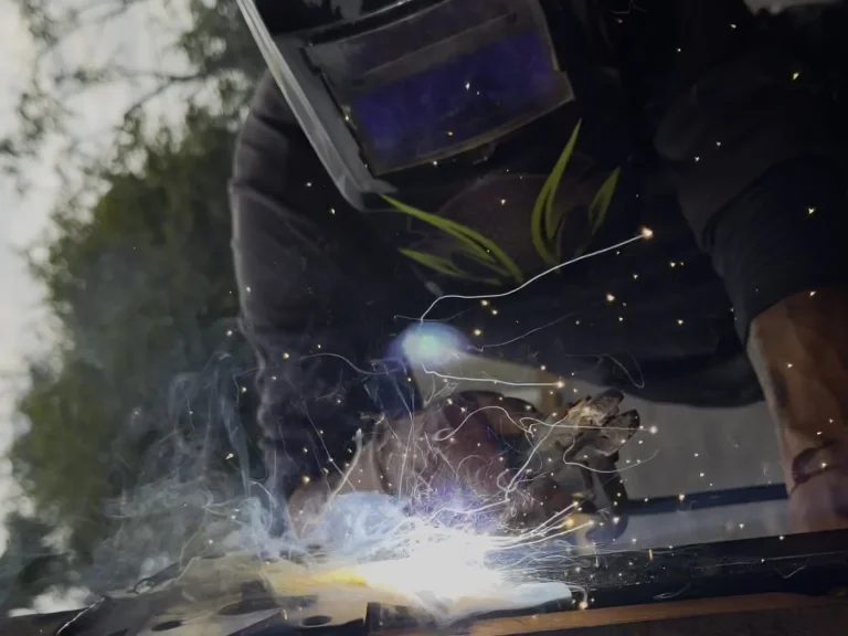 Technician welding a wrought iron gate hinge during a repair job in Mansfield, TX