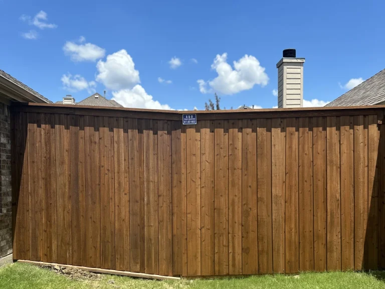 Finished dark-stained cedar fence with cap and trim in Royse City, TX