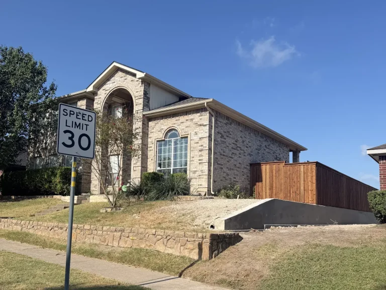 Stone home exterior with a newly installed cedar side fence in Mansfield, TX