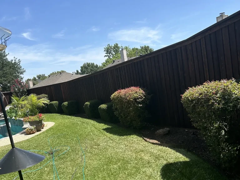 Repaired dark-stained cedar fence enclosing a landscaped backyard in Arlington, TX